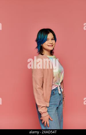 Asiatisches Mädchen mit blauen Haaren steht stilvoll vor einer pinkfarbenen Wand in einem Studio-Setting. Stockfoto