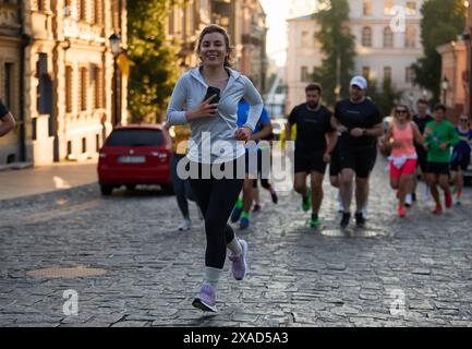Fröhliche ukrainische Frau, die früh am Morgen zusammen mit einer Gruppe von Athleten läuft. Gesunder Lebensstil in Kiew - 1. Juni 2024 Stockfoto