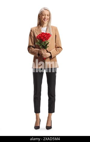Porträt einer Geschäftsfrau in voller Länge, die einen Haufen roter Rosen auf weißem Hintergrund betrachtet Stockfoto