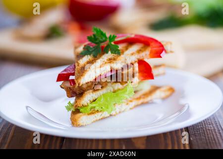 Gebratener Toast mit Huhn, Salat, Gemüse auf einem Holztisch. Stockfoto