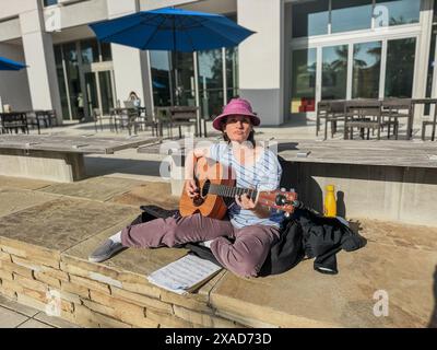 Santa Barbara, Kalifornien, USA, 4. Juni 2024. Tova Morrison von Santa Barbara spielt und singt israelische Lieder auf Hebräisch auf ihrer Gitarre vor dem Summit Cafe und der Bibliothek, als friedlicher und subtiler Gegenprotest gegen das nahe gelegene Offensive und antisemitische Pro-Palästina-Lager auf dem UCSB Campus am 3. Juni 2024. nachdem die Stürmer der UAW den zweiten Tag ihres Streiks an diesem Ort beendet hatten. Eine Palme wirft einen langen Schatten in den Vordergrund. (Kreditbild: © Amy Katz/ZUMA Press Wire) NUR REDAKTIONELLE VERWENDUNG! Nicht für kommerzielle ZWECKE! Stockfoto