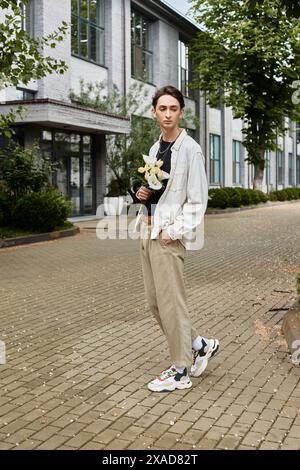 Ein stilvoller junger Mann in einer braunen Jacke und Turnschuhen geht selbstbewusst auf einem gemauerten Gehweg und strahlt Stolz und Individualität aus. Stockfoto