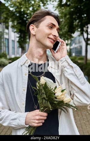 Ein junger Schwuler in stilvoller Kleidung jongliert mit einem Blumenstrauß, während er telefoniert. Stockfoto