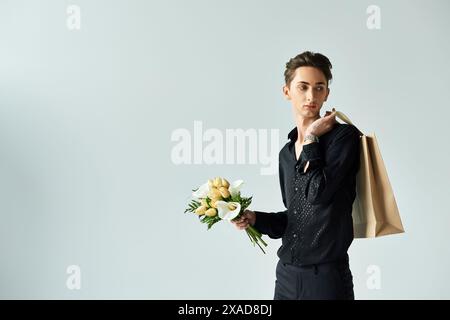 Eine junge queere Person posiert selbstbewusst mit einer Einkaufstasche voller Blumen und drückt Stolz und Freude aus. Stockfoto