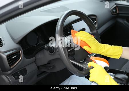 Frau, die das Lenkrad mit Lappen im Auto reinigt, Nahaufnahme Stockfoto