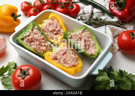 Rohe gefüllte Paprika und Zutaten auf weißem Tisch Stockfoto