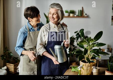 Zwei schürzenbekleidete Frauen pflegen eine Topfpflanze in perfekter Harmonie. Stockfoto