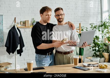 Zwei Männer in einem Büro diskutieren leidenschaftlich über Ideen auf einem Laptop. Stockfoto