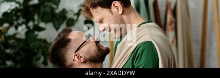 Schwule Paare teilen einen zärtlichen Moment im kreativen Designprozess für Kleidung. Stockfoto