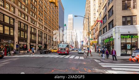 New York City, USA - 26. August 2017: An der Ecke Seventh Avenue und West 30th Street, mit Autos, einem Feuerwehrwagen und Menschen, die zu Fuß unterwegs sind. Stockfoto