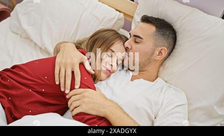 Ein liebevolles Paar kuschelt sich im Bett und zeigt Intimität und Zuneigung in einer gemütlichen Schlafzimmerumgebung. Stockfoto