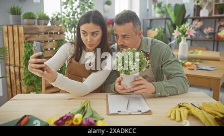 Ein Mann und eine Frau machen ein Selfie in einem Blumenladen, umgeben von Pflanzen und Blumenarrangements. Stockfoto