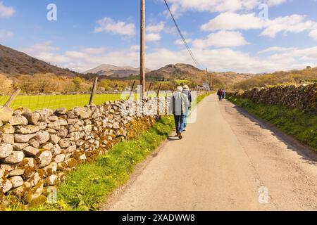 Touristen wandern im Esk-Tal in Richtung Boot-Dorf inmitten von Trockenmauern im Lake District National Park, Cumbria, England, Großbritannien. Stockfoto