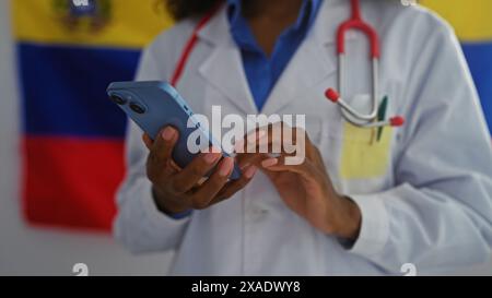 Eine afroamerikanische Ärztin benutzt ein Smartphone vor einer venezolanischen Flagge in einer Innenwahl. Stockfoto