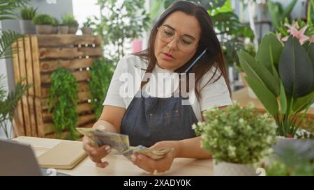 Eine beschäftigte Frau, die in einem Blumenladen rumänische Währung zählt, mit einem Telefon auf der Schulter. Stockfoto