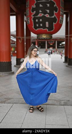 Die sprudelnde hispanische Frau tanzt fröhlich und dreht sich in wunderschönem Kleid inmitten der herrlichen Architektur des Senso-JI-Tempels in tokio. Sie ist durch japan gereist Stockfoto