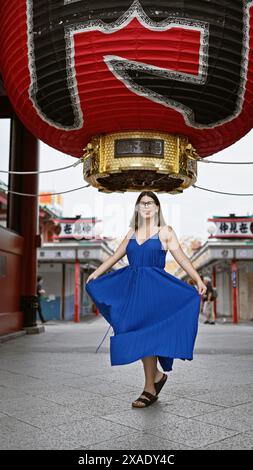 Die sprudelnde hispanische Frau tanzt fröhlich und dreht sich in wunderschönem Kleid inmitten der herrlichen Architektur des Senso-JI-Tempels in tokio. Sie ist durch japan gereist Stockfoto