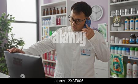 Ein junger, gutaussehender chinese, der einen weißen Mantel trägt, spricht am Telefon, während er in einer Apotheke arbeitet, wobei verschiedene Drogeriemarktprodukte ausgestellt werden Stockfoto