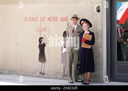 Ein Paar in zeitlicher Kleidung in Arromanches in der Normandie, Frankreich, während der Gedenkfeier zum 80. Jahrestag der Landung des D-Day. Bilddatum: Donnerstag, 6. Juni 2024. Stockfoto