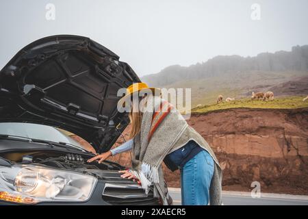 Eine Frau steht neben einem Auto mit gezogener Kapuze, Tourist in der peruanischen Andesmyla Stockfoto