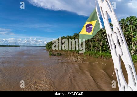 Brasilianische Flagge auf dem Boot segeln auf dem Fluss im Amazonas-Regenwald wunderschöne Landschaft. Konzept der Erhaltung, Umwelt, Ökologie, Symbol, Natur, Klima. Stockfoto