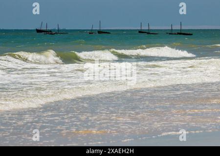 Eine kleine Gruppe von Dows am türkisfarbenen Wasser der Küste von Inhassoro in Mosambik mit dem trüben Blick auf die Insel Bazaruto im Hintergrund. Stockfoto