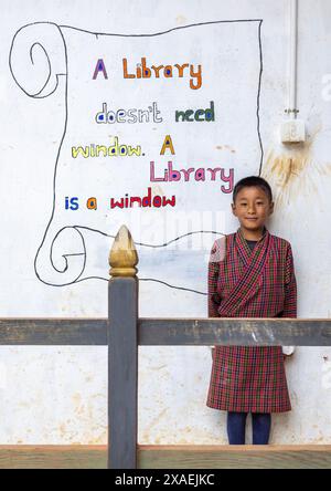 Porträt eines Jungen vor einem Wandgemälde, das Bücher in der Rubesa Primary School, Wangdue Phodrang, Rubesagewog, Bhutan fördert Stockfoto