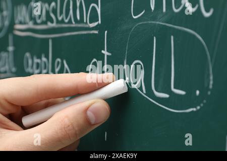 Englischlehrer schreibt mit Kreide auf grüner Tafel, Großaufnahme Stockfoto