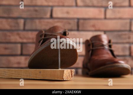 Metallnagel in Holzplanke und Schuhe auf dem Tisch Stockfoto