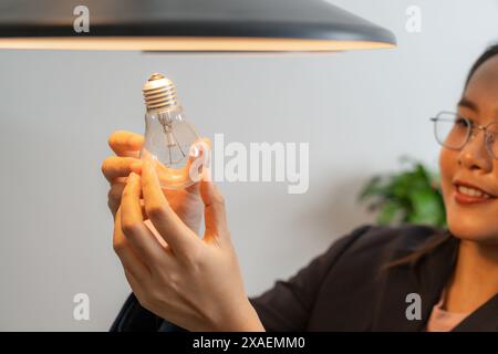 Die junge Frau wechselt zu Hause Glühbirnen Stockfoto