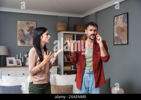 Ein junges Paar ruft die Polizei an, um häusliche Gewalt zu melden. Mann und Frau rufen 911 an, um laute Geräusche von der Wohnung oben zu melden, streiten und schreiende Stimmen. Stockfoto