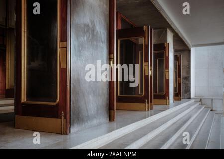 Aus nächster Nähe ein eleganter Eingang mit mehreren Holzglastüren mit Messinggriffen und Akzenten, die in einer Architektur Marmortreppen hinaufführen Stockfoto