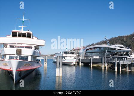 Ein großes weißes Boot liegt neben einem kleineren Boot an. Das Wasser ist ruhig und der Himmel ist klar Stockfoto