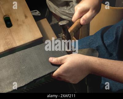 Schuhmacherhände mit Hammer, die die Schuhsohle reparieren. Handel, Geschäft. Stockfoto