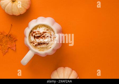 Herbst Gewürz Latte oder heiße Schokolade in einem Kürbisbecher auf orangem Hintergrund, Herbststillleben Stockfoto