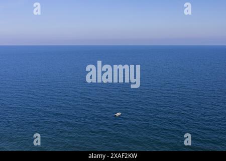 Panoramafoto der Adria mit einem kleinen weißen Motorboot und einer winzigen gelben Boje an sonnigem Tag Stockfoto