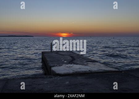 Foto des Sonnenuntergangs an der Adria mit einem winzigen verlassenen Anlegeplatz in der Küstenstadt Piran in Slowenien Stockfoto