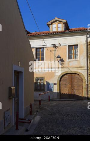 Foto einer alten Straße mit kleinem, rot gefärbtem Haus mit Holztüren am sonnigen Tag in der alten slowenischen Stadt Piran Stockfoto