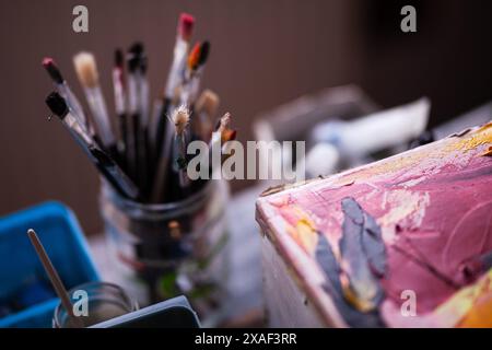 Detaillierte Ansicht verschiedener Pinsel und eine lebendige, farbige Palette, die die Werkzeuge eines Künstlers darstellt. Stockfoto