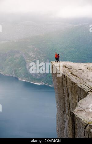 Preikestolen, Norwegen, zwei Menschen stehen am Rande einer Klippe mit Blick auf einen Fjord in Norwegen. Die Klippe ist bekannt als Preikestolen oder Kanzel Rock und ist ein beliebtes Touristenziel. Stockfoto