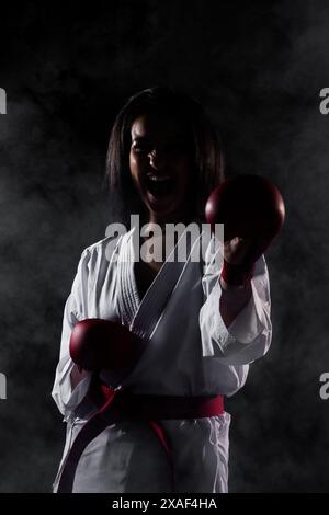 Schönes Mädchen Ausübung Karate Pose und Schreien vor Nebel Hintergrund Stockfoto