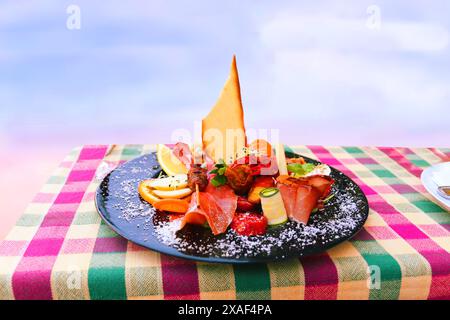 Traditionelle italienische Küche. Nahaufnahme von gemischten mediterranen Vorspeisen oder Antipasto und Tapas mit Schinkengemüse und Krabben auf schwarzem Teller auf dem Tisch darüber Stockfoto