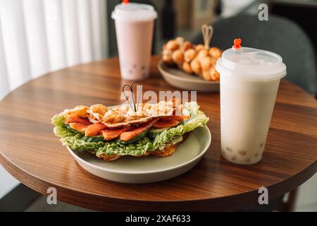 Sandwiches Waffeln mit Fleisch, Käse und Kräutern auf Teller mit Getränken auf Holztisch Stockfoto