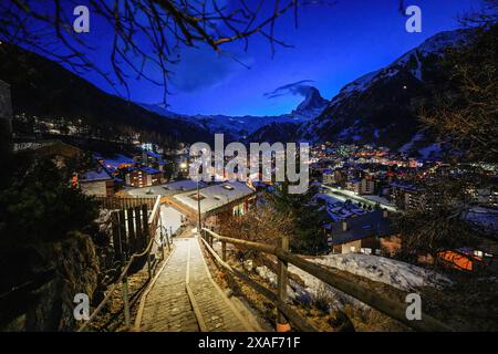 Pfad, der zu einem Aussichtspunkt über dem Dorf Zermatt führt, mit Blick auf das Matterhorn in den Schweizer Alpen im Winter bei Nacht Stockfoto