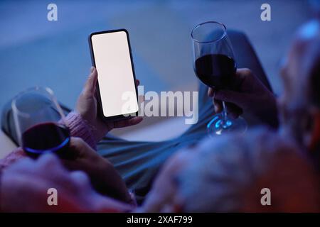 Großansicht eines nicht erkennbaren Paares, das ein Smartphone mit leerem weißen Bildschirm hält und die mobile App verwendet Stockfoto