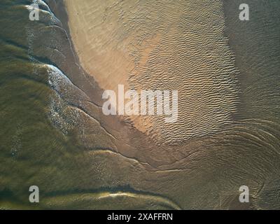 Ein Blick aus der Vogelperspektive direkt nach unten und zeigt Wellen, die um eine Sandbank in der Mündung des Flusses Avon bei Ebbe, Devon, Großbritannien, wehen. Stockfoto