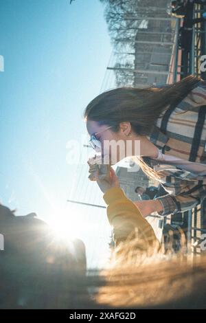 Eine Gruppe von Teenagern sitzt draußen auf einem Basketballfeld mit Ständen, isst Kebab, spielt Basketball, hat Spaß zusammen, hört Musik. Stockfoto