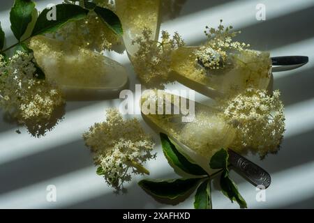 Gefrorene weiße Holunderblüten in Wasser in Form von Eis auf einem weißen Tisch. Stockfoto