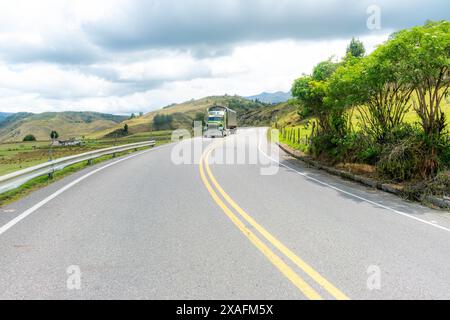 Bergige Landschaft mit einer Straße, die am Horizont verschwindet, mit einem Lastwagen, der an einem kalten Tag entlang fährt Stockfoto