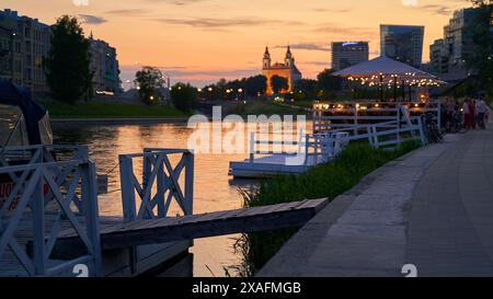 Vilnius bei Sonnenuntergang Panoramablick auf die Stadt mit Fluss Neris, Booten, Café, Kirche und Wolkenkratzern des New Center. Litauen, baltische staaten. Stockfoto